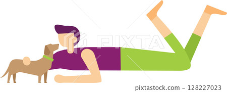 Young man with purple shirt and green trousers is lying on his stomach with legs raised and playing with his brown dachshund dog, wearing a green collar 128227023