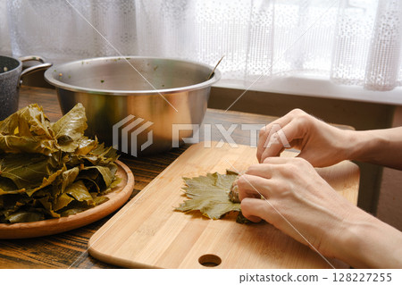 Preparation of dolma using grape leaves and fresh ingredients in a cozy kitchen setting Preparation of dolma using grape leaves and fresh ingredients in a cozy kitchen setting 128227255