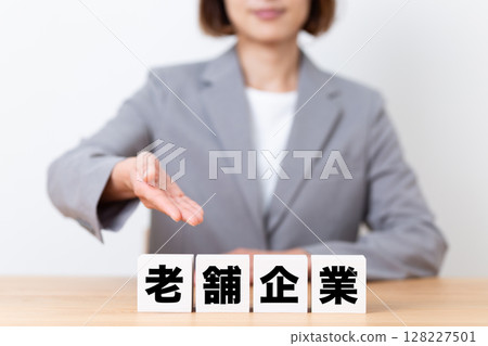 A middle-aged female business woman wearing a suit and a block of a long-established company A middle-aged female business woman wearing a suit and a block of a long-established company 128227501