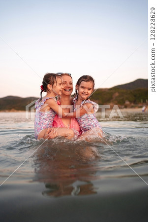 Family enjoying a fun day at the beach during sunset 128228629