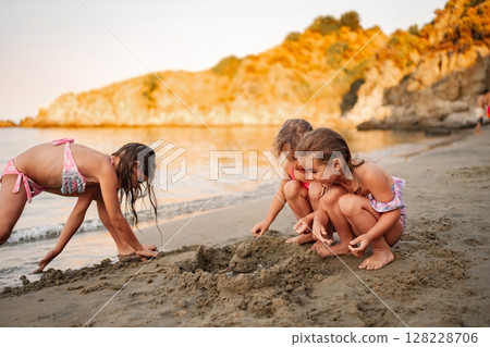 Family enjoying quality time building sandcastles at the beach 128228706