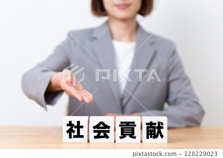 A middle-aged female business woman wearing a suit and a social contribution block 128229023