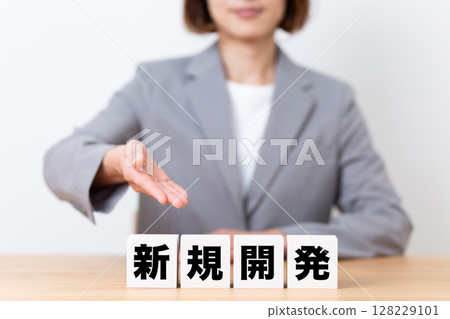 A middle-aged female business woman wearing a suit and a block of new development 128229101