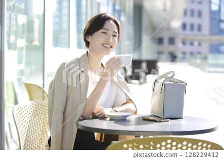 A woman taking a coffee break on a cafe terrace 128229412