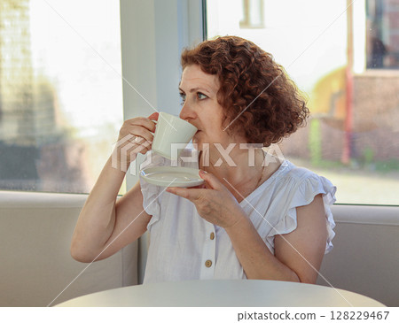 Woman enjoying a cup of hot tea in a cozy indoor setting 128229467
