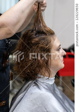 Woman receiving a haircut at a professional salon hairstyling session 128229650