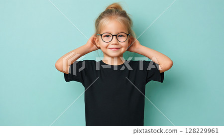 Young girl in black t-shirt for mockup with glasses smiling cheerfully while holding her hair back against a light blue background 128229961