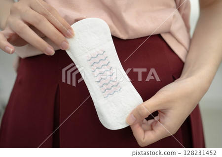 Asian woman holding sanitary napkin pad for hygiene menstrual period cycle protection. Asian woman holding sanitary napkin pad for hygiene menstrual period cycle protection. 128231452