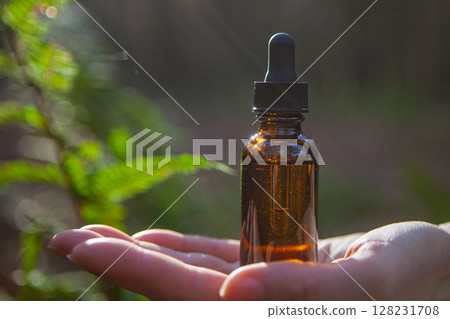 Amber Dropper Bottle Held in Sunlight Outdoors 128231708