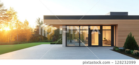 Modern house exterior with large windows and sunset lighting in a serene landscape 128232099