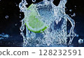 Fresh lime splashes into clear water creating ripples and droplets under soft lighting in a dark setting 128232591