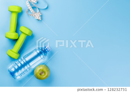 Flat lay of dumbbells, water bottle, and green apple over a bright blue Flat lay of dumbbells, water bottle, and green apple over a bright blue 128232731