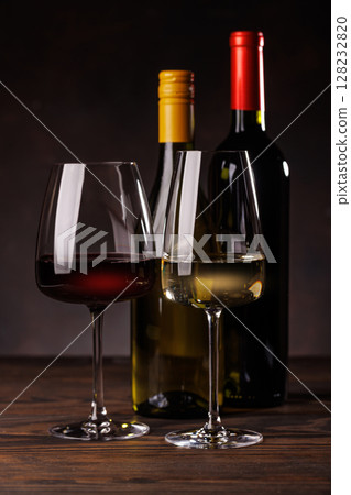 Wine glasses filled with wine beside a bottles 128232820