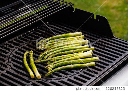Fresh asparagus spears sizzling on a hot grill 128232823