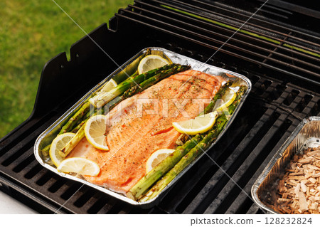Grilled salmon fillets and asparagus sizzling on a barbecue grill 128232824