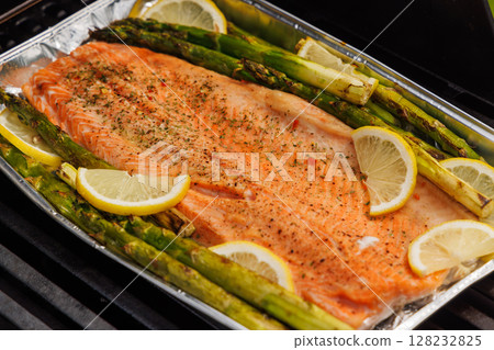 Grilled salmon fillets and asparagus sizzling on a barbecue grill 128232825