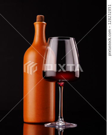 Elegant presentation of red wine in a glass and a bottle against a dark background Elegant presentation of red wine in a glass and a bottle against a dark background 128232851