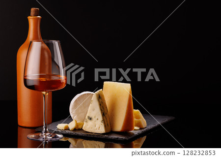 A refined selection of aged cheeses presented on a board, accompanied by a glasses of wine A refined selection of aged cheeses presented on a board, accompanied by a glasses of wine 128232853