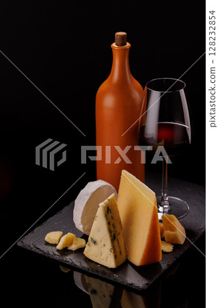 A refined selection of aged cheeses presented on a board, accompanied by a glasses of wine A refined selection of aged cheeses presented on a board, accompanied by a glasses of wine 128232854