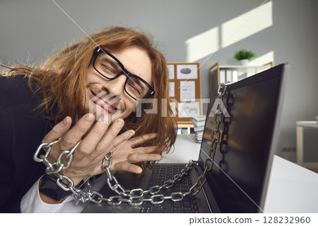 Tired employee crying because he's chained to his office computer and can't go home Tired employee crying because he's chained to his office computer and can't go home 128232960