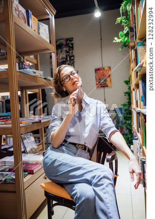 Woman in glasses reading in library Woman in glasses reading in library 128232994