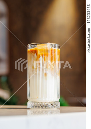 Iced latte in a clear glass with visible coffee and milk layers 128233488