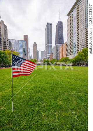 American flag on a green grass field surrounded by buildings in downtown Chicago 128233567