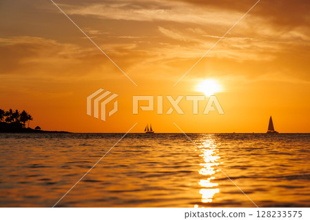 Sunset over the sea with sailing boats on the horizon Sunset over the sea with sailing boats on the horizon 128233575