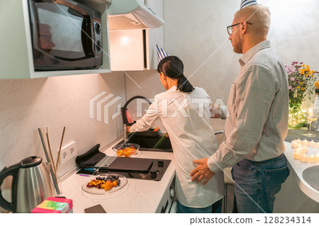 Couple Cooking Kitchen Apartment: Young couple prepares food in modern apartment kitchen; enjoying domestic life. Couple Cooking Kitchen Apartment: Young couple prepares food in modern apartment kitchen; enjoying domestic life. 128234314