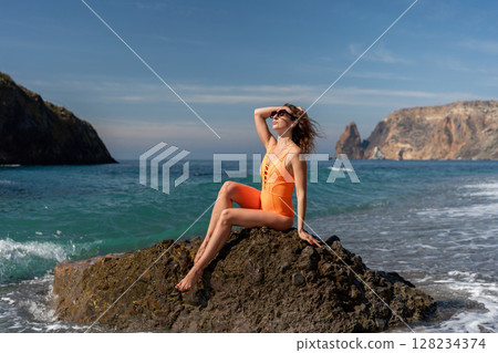 Beach Woman Summer: Woman in swimsuit relaxes on rock at beach during summer for vacation. 128234374