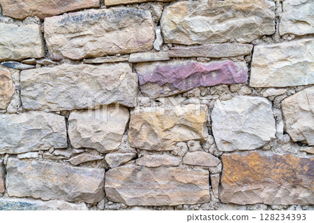 A wall made of stone with a few pink and purple spots 128234393