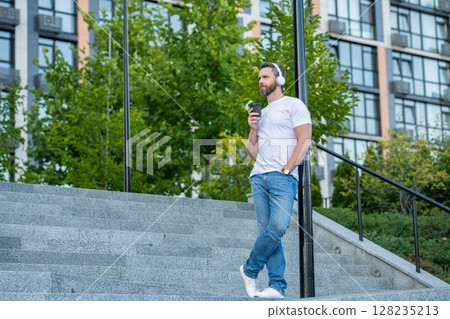 man in music headphones in the street with copy space. man in music headphones outside. 128235213