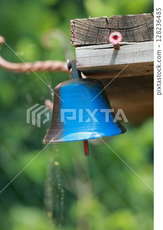 Blue bell hanging from a wooden post 128236485