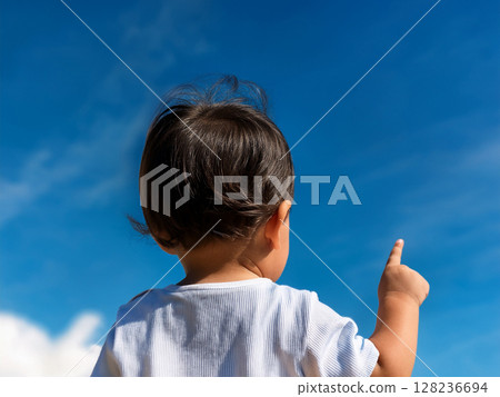 A child raising his hands high into the blue sky 128236694