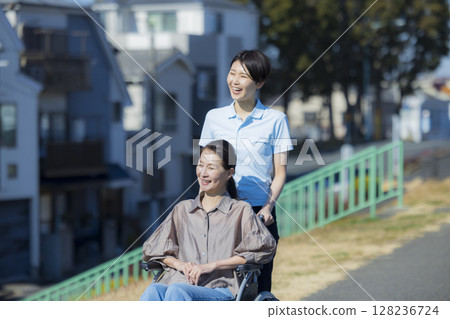 一名女性護理人員推著一位坐在輪椅上的婦女 128236724