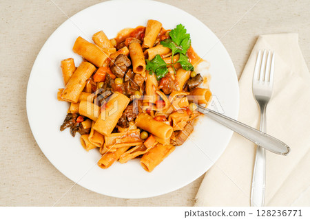 Delicious beef stew with rigatoni pasta, vegetables, and parsley garnish Delicious beef stew with rigatoni pasta, vegetables, and parsley garnish 128236771