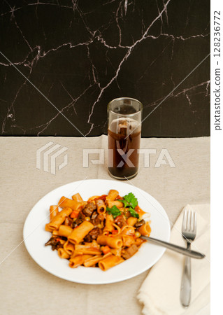 Delicious pasta with meat and vegetables enjoyed with refreshing dark drink Delicious pasta with meat and vegetables enjoyed with refreshing dark drink 128236772