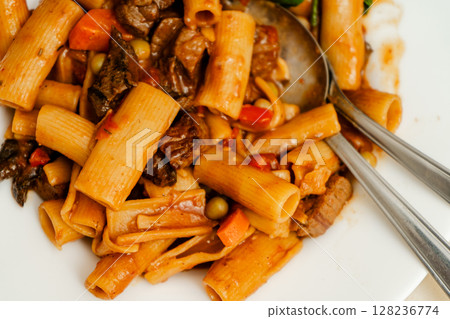 Delicious pasta with beef stew and vegetables being mixed with silver cutlery Delicious pasta with beef stew and vegetables being mixed with silver cutlery 128236774