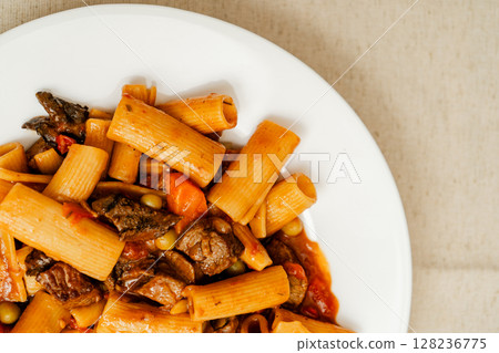 Delicious beef stew with rigatoni pasta, peas, carrots, and mushrooms on white plate 128236775