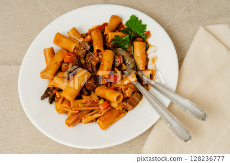 Delicious beef stew with rigatoni pasta and vegetables garnished with parsley 128236777