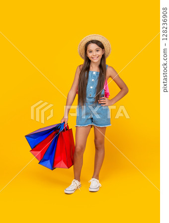 positive teen kid with shopping bags on yellow background. full length 128236908