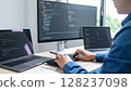 The hands of a male engineer operating a keyboard. An image of programming on multiple monitors. 128237098