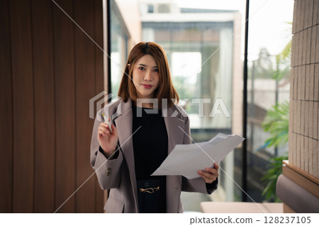 Portrait of a successful business woman with inspiration from their excellent financial results front at the desk, looking to camera. Portrait of a successful business woman with inspiration from their excellent financial results front at the desk, looking to camera. 128237105