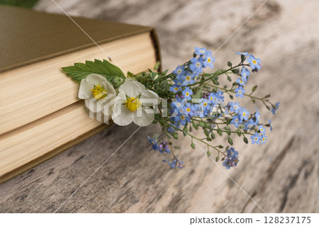 Wildflowers between book pages on rustic wooden table 128237175