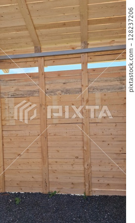 Wooden shed structure with vertical planks and open sky view 128237206