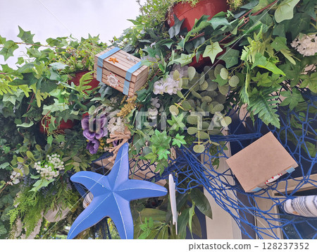 Lush greenery with decorative boxes and blue starfish accents 128237352