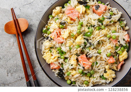 Healthy diet stir fry rice with salmon, seaweed, green peas, onion and egg close-up in bowl. Horizontal top view Healthy diet stir fry rice with salmon, seaweed, green peas, onion and egg close-up in bowl. Horizontal top view 128238856