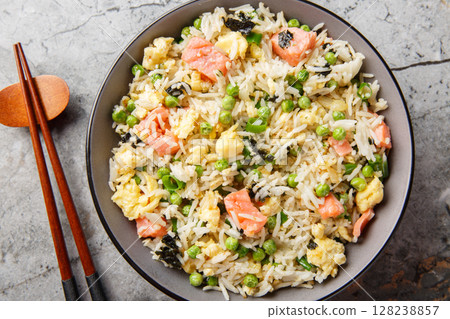 Salmon fried rice with egg, seaweed and vegetables close-up on bowl. Horizontal top view Salmon fried rice with egg, seaweed and vegetables close-up on bowl. Horizontal top view 128238857