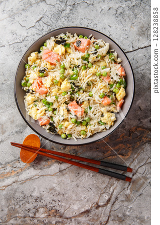 Stir fry rice with salmon, egg, green peas, onion and seaweed close-up in bowl. Vertical top view Stir fry rice with salmon, egg, green peas, onion and seaweed close-up in bowl. Vertical top view 128238858