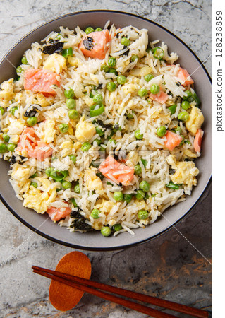 Fried rice with vegetables, salmon, egg and seaweed close-up in bowl. Vertical top view 128238859